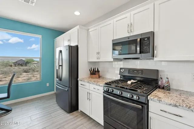 a kitchen with stainless steel appliances white cabinets a stove a refrigerator and a microwave