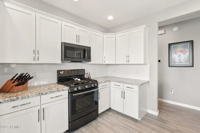 a kitchen with white cabinets and black appliances