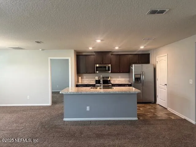 a view of a kitchen with stainless steel appliances granite countertop a stove and a refrigerator