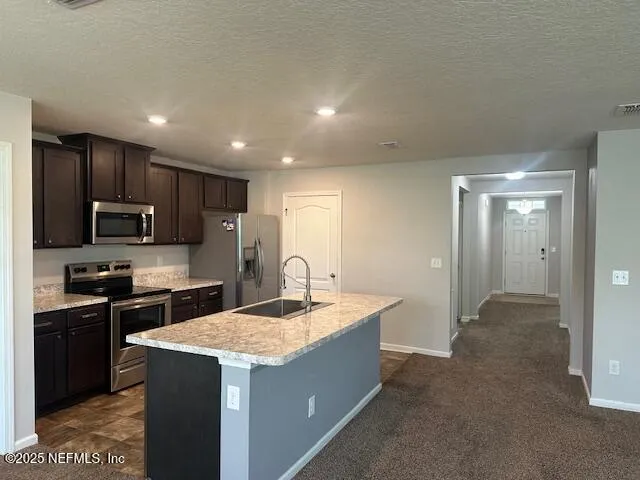 a kitchen with kitchen island granite countertop stainless steel appliances sink stove microwave and cabinets