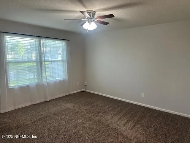an empty room with windows and fan