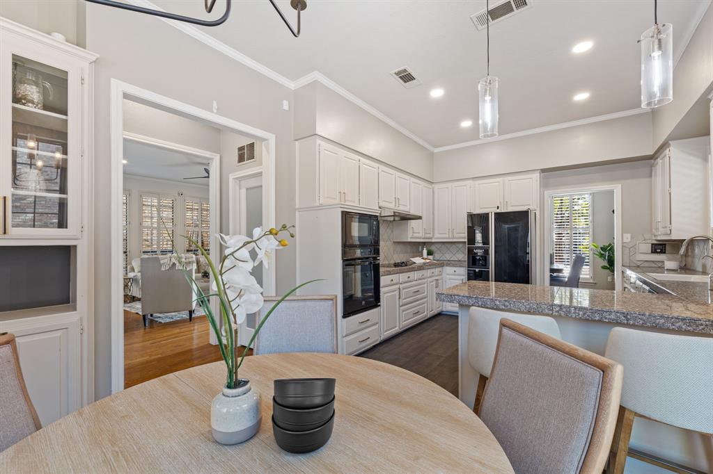 4134 Crossing Lane Dallas, TX 75220 - Photo 18 of 39 Kitchen with tile counters, white cabinets, crown molding, a peninsula, and decorative light fixtures