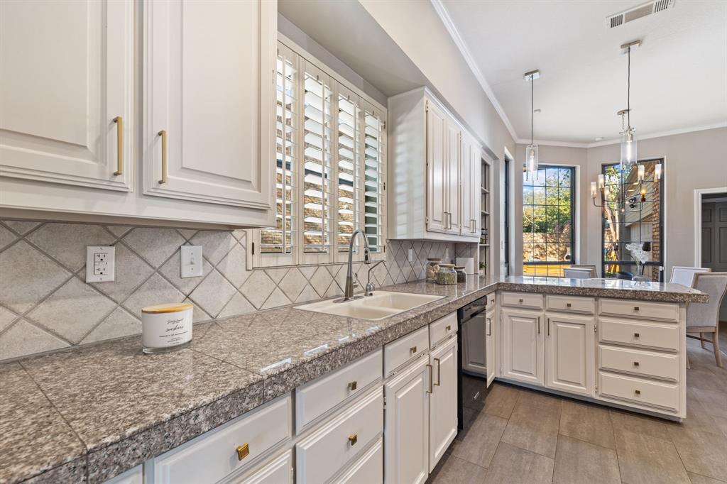 4134 Crossing Lane Dallas, TX 75220 - Photo 8 of 39 Kitchen featuring tile counters, a peninsula, crown molding, tasteful backsplash, and pendant lighting