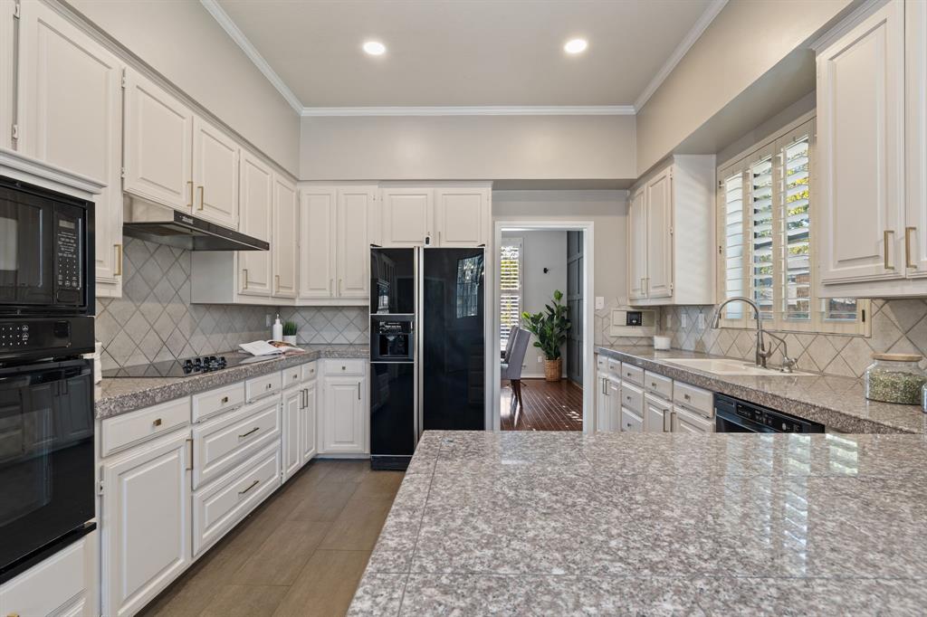 4134 Crossing Lane Dallas, TX 75220 - Photo 9 of 39 Kitchen with tile counters, white cabinets, black appliances, ornamental molding, and tasteful backsplash