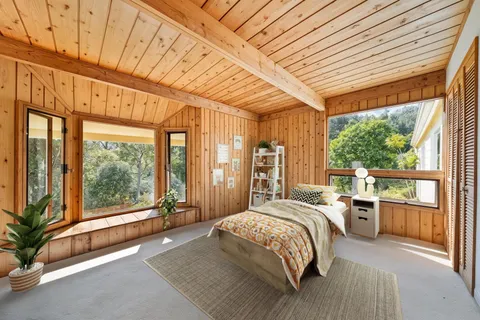 a bedroom with a large bed and large windows