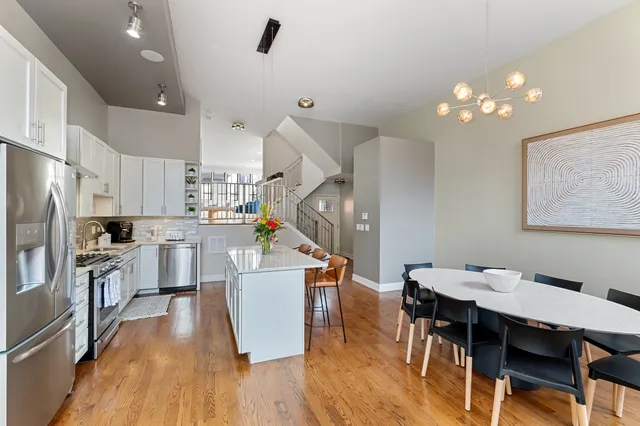 a kitchen with stainless steel appliances kitchen island hardwood floor and white cabinets