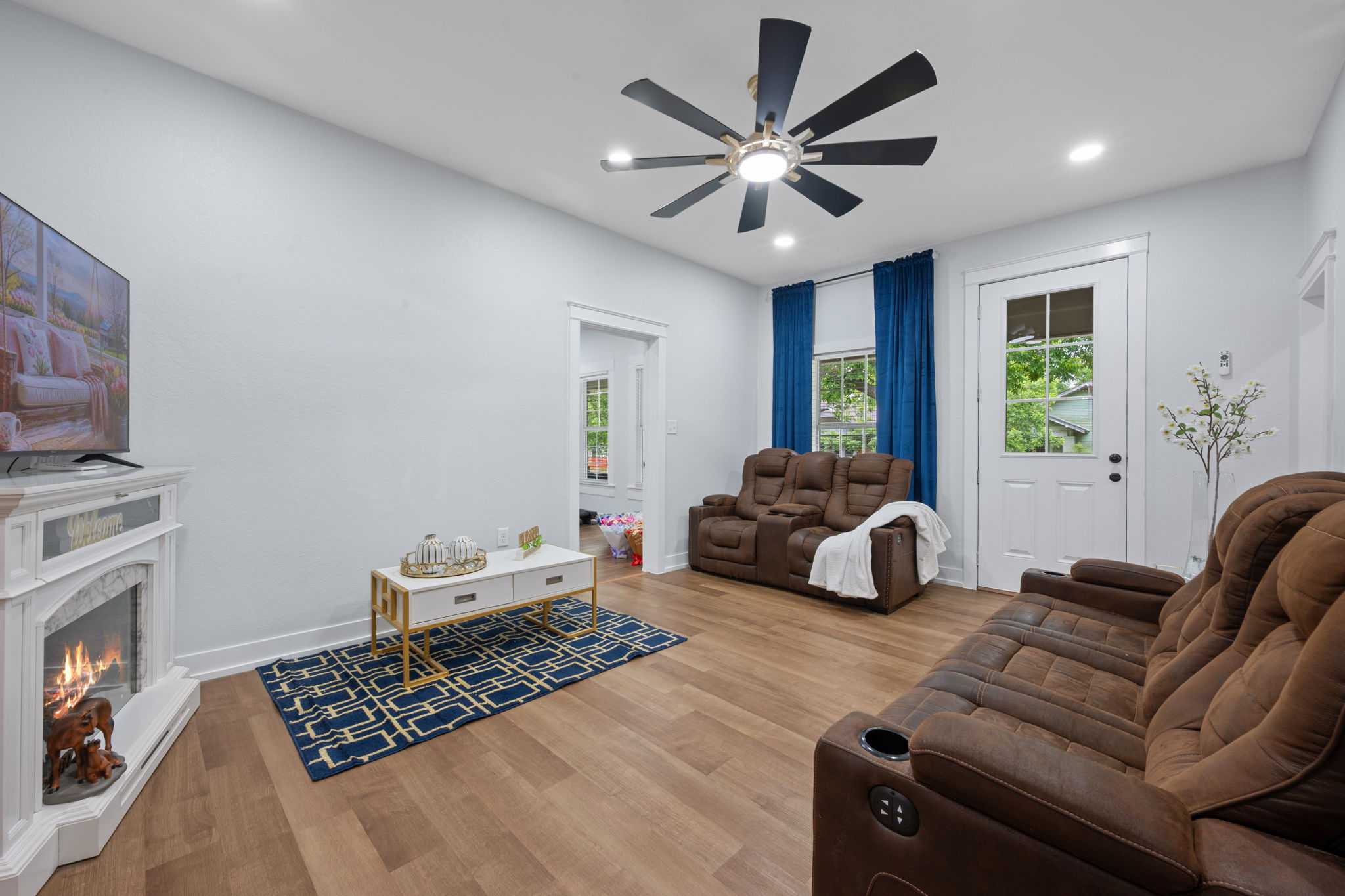 602 East 6th Street Cameron, TX 76520 - Photo 8 of 40 Living area featuring wood-finish flooring, a decorative corner fireplace, recessed ceiling lighting, a modern ceiling fan, and a glass-paneled exterior door