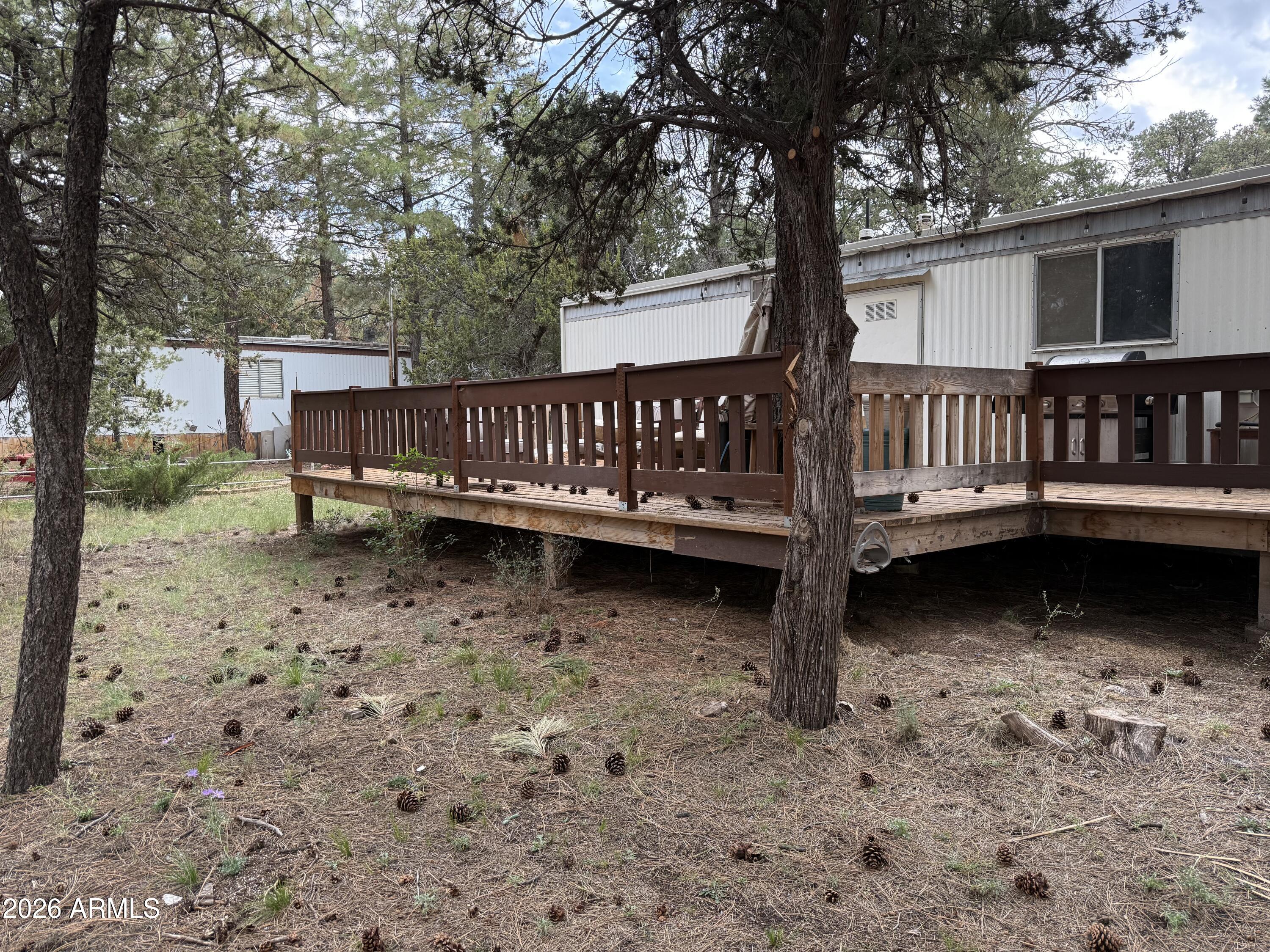 a view of a deck in the backyard with large trees