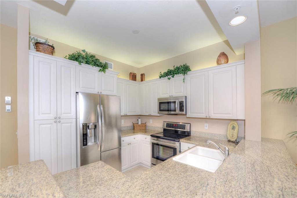 450 Launch Circle, Unit 203 Naples, FL 34108 - Photo 4 of 24 a kitchen with stainless steel appliances a refrigerator a stove top oven a sink and dishwasher