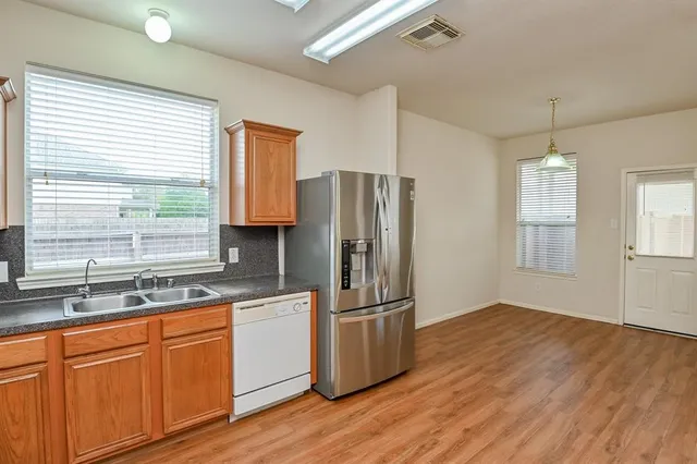 a kitchen with stainless steel appliances granite countertop a refrigerator a sink and white cabinets