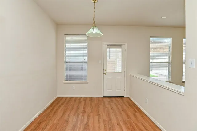 an empty room with wooden floor exposed radiator and windows