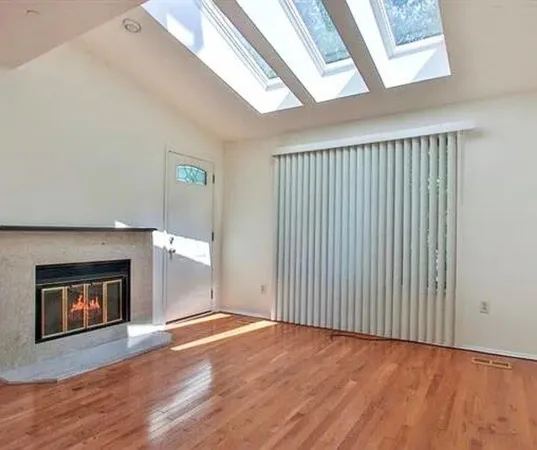 a view of a big room with wooden floor and windows