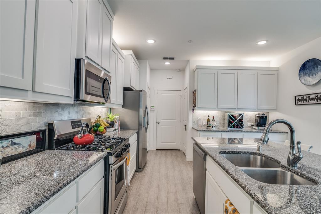 2724 Splendor Lane Little Elm, TX 75068 - Photo 10 of 25 a kitchen with granite countertop a sink stainless steel appliances and cabinets