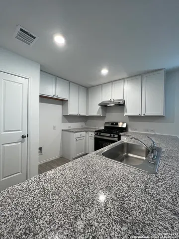 a kitchen with granite countertop a sink and cabinets