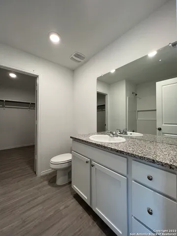 a bathroom with a granite countertop sink a toilet and a mirror