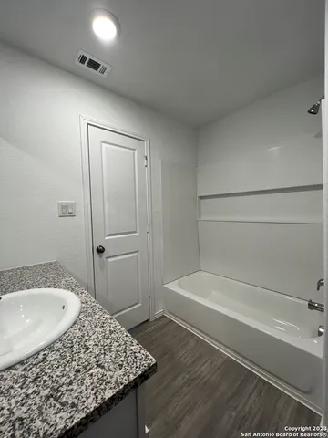 a bathroom with a granite countertop sink and a bathtub