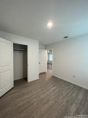 a view of an empty room with wooden floor and closet