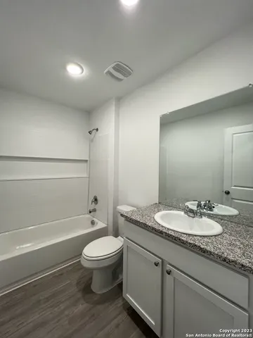 a bathroom with a granite countertop toilet a sink and a mirror