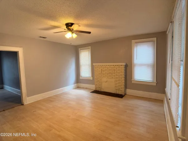 an empty room with windows and ceiling fan