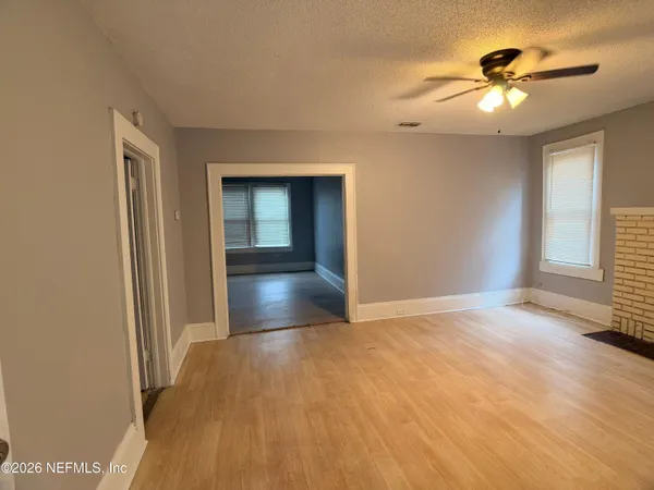 a view of an empty room with window and wooden floor