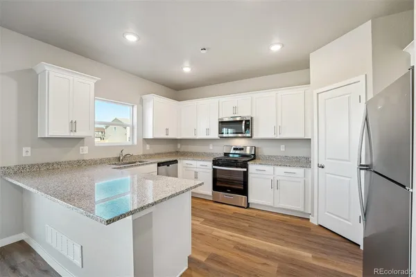 a kitchen with granite countertop a refrigerator stove top oven and sink