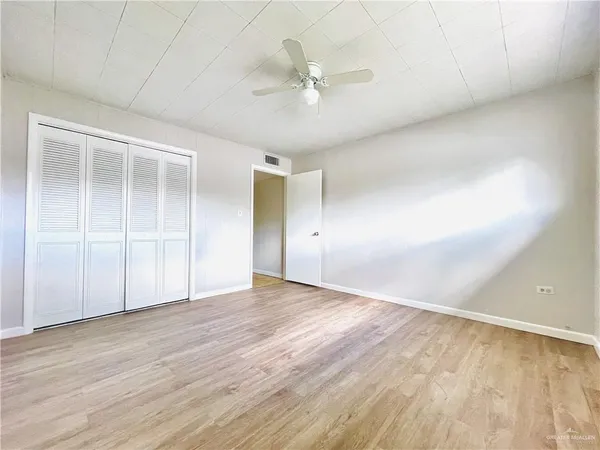 an empty room with wooden floor and fan