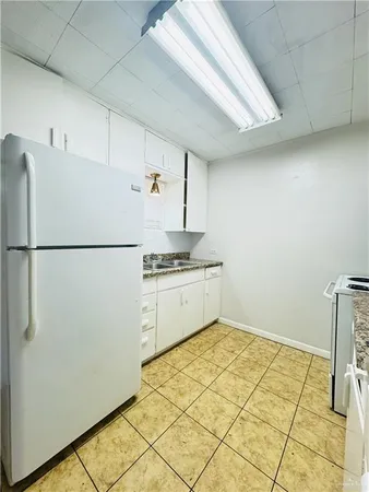 a kitchen with a refrigerator and white cabinets