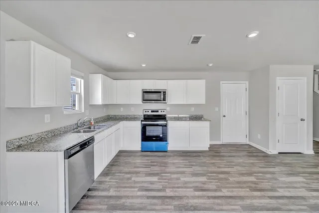 a kitchen with granite countertop a sink stove and cabinets