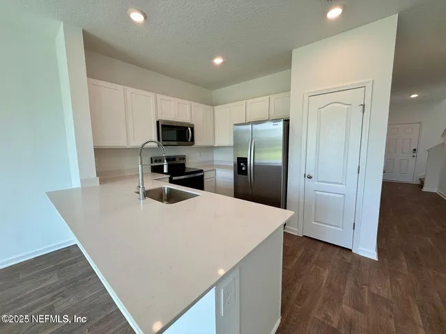 a kitchen with stainless steel appliances a refrigerator and a stove top oven
