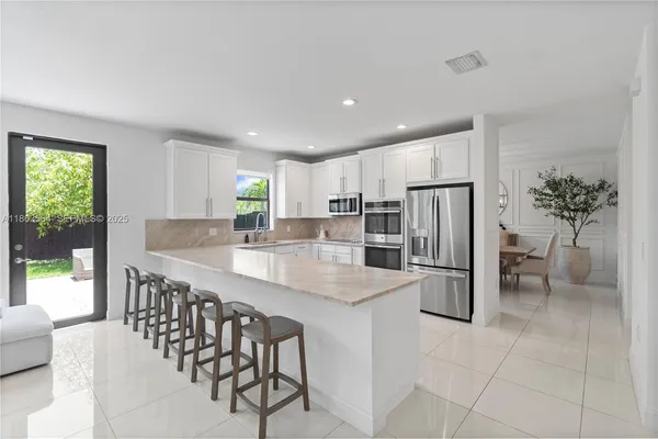 a large white kitchen with a refrigerator and a sink
