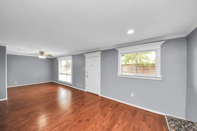 a view of an empty room with a window and wooden floor