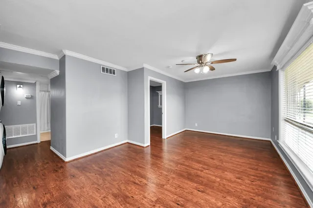 a view of empty room with wooden floor and kitchen view