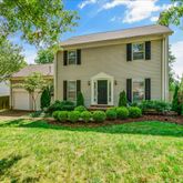 a front view of a house with a yard and trees