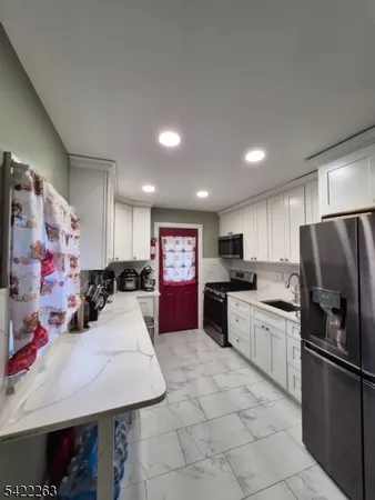 a kitchen with stainless steel appliances kitchen island granite countertop a refrigerator and a sink