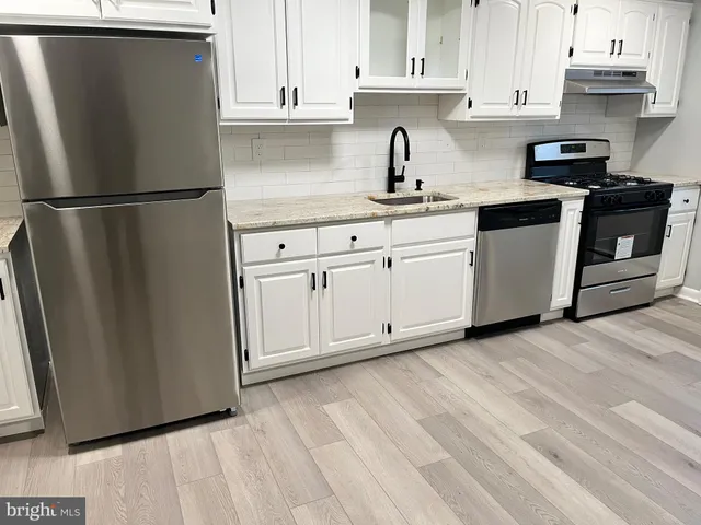 a kitchen with stainless steel appliances granite countertop a refrigerator sink and white cabinets