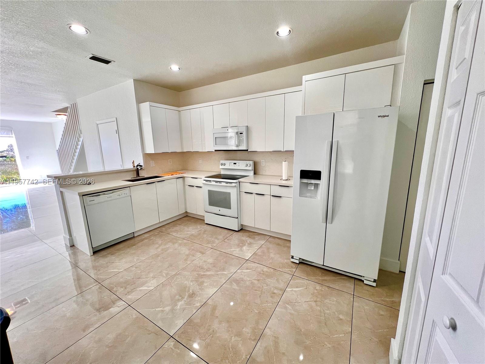 a kitchen with white cabinets and white appliances