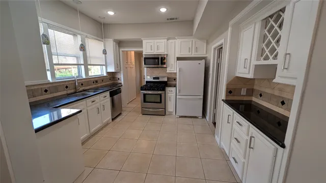 a large kitchen with stainless steel appliances a refrigerator sink and stove