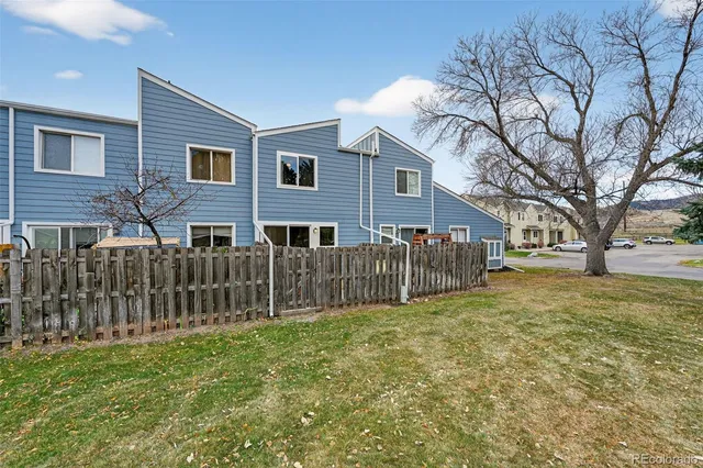 a view of a backyard with large trees and wooden fence