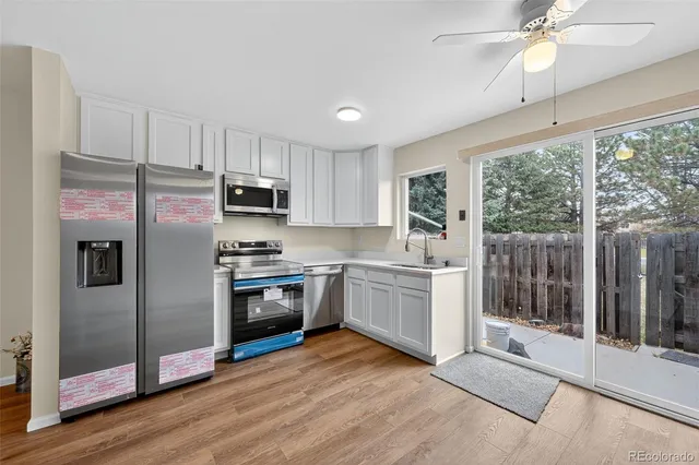 a kitchen with granite countertop a refrigerator oven a sink and wooden floors