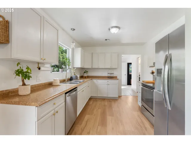 a kitchen with stainless steel appliances granite countertop a sink refrigerator and cabinets