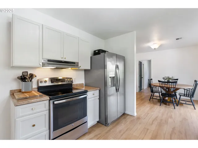 a kitchen with stainless steel appliances a stove a refrigerator and a dining table