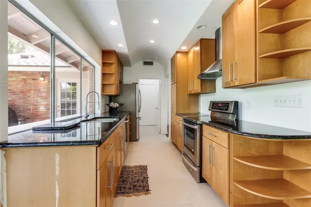 a kitchen with stainless steel appliances granite countertop a sink a stove and a refrigerator