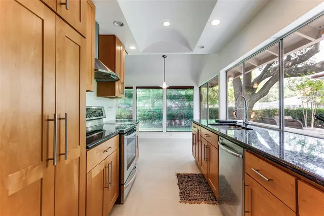 a kitchen with stainless steel appliances granite countertop a stove a sink and a refrigerator