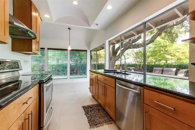 a kitchen with stainless steel appliances wooden cabinets a sink and a large window