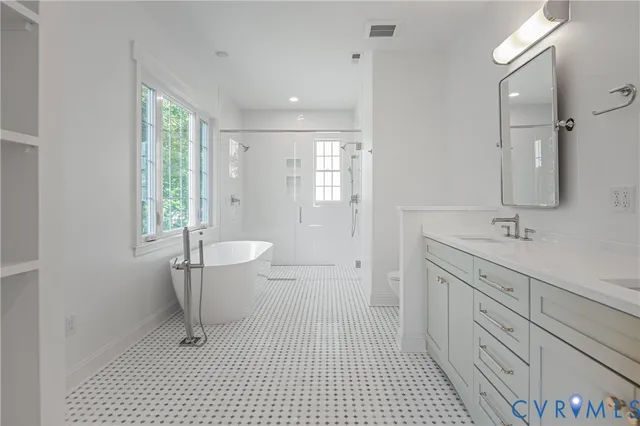 a spacious bathroom with a double vanity sink a toilet and a shower
