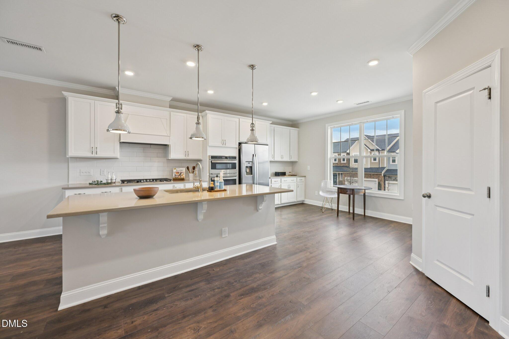 8405 Zinc Autumn Path Raleigh, NC 27615 - Photo 6 of 24 a kitchen with stainless steel appliances granite countertop a refrigerator oven a sink and white cabinets with wooden floor