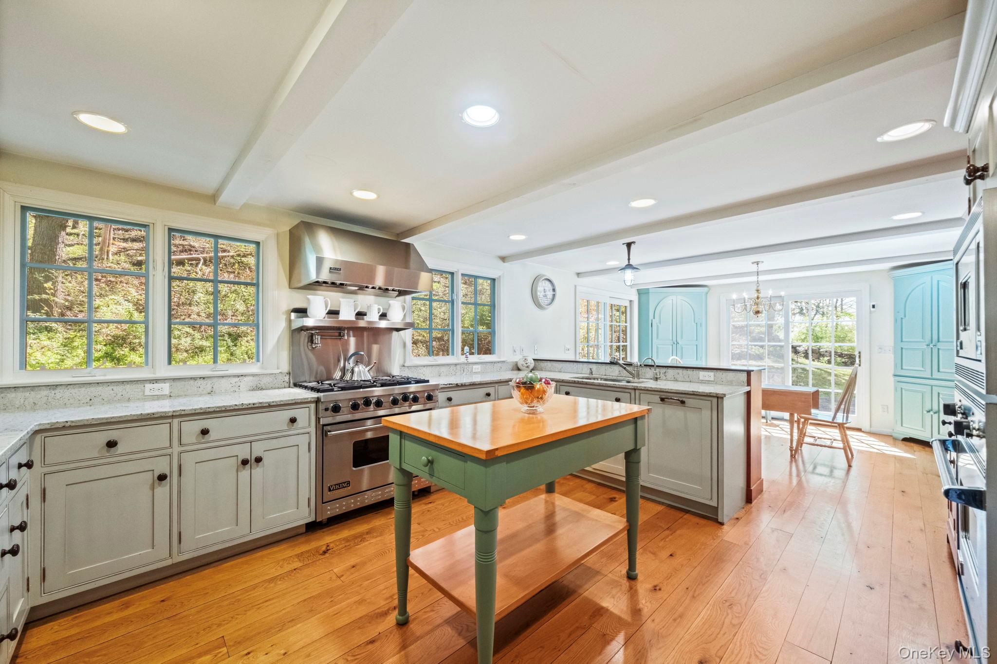 12 Harris Road Katonah, NY 10536 - Photo 4 of 38 a kitchen with stainless steel appliances granite countertop a stove top oven a sink a dining table and chairs with wooden floor