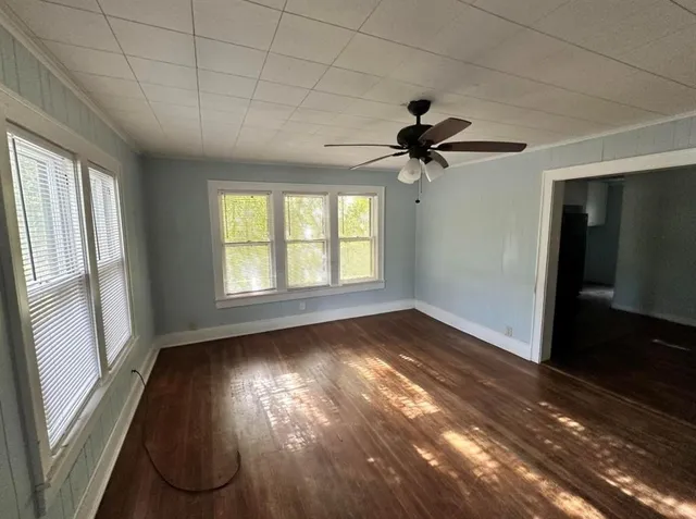 a view of an empty room with a window and wooden floor