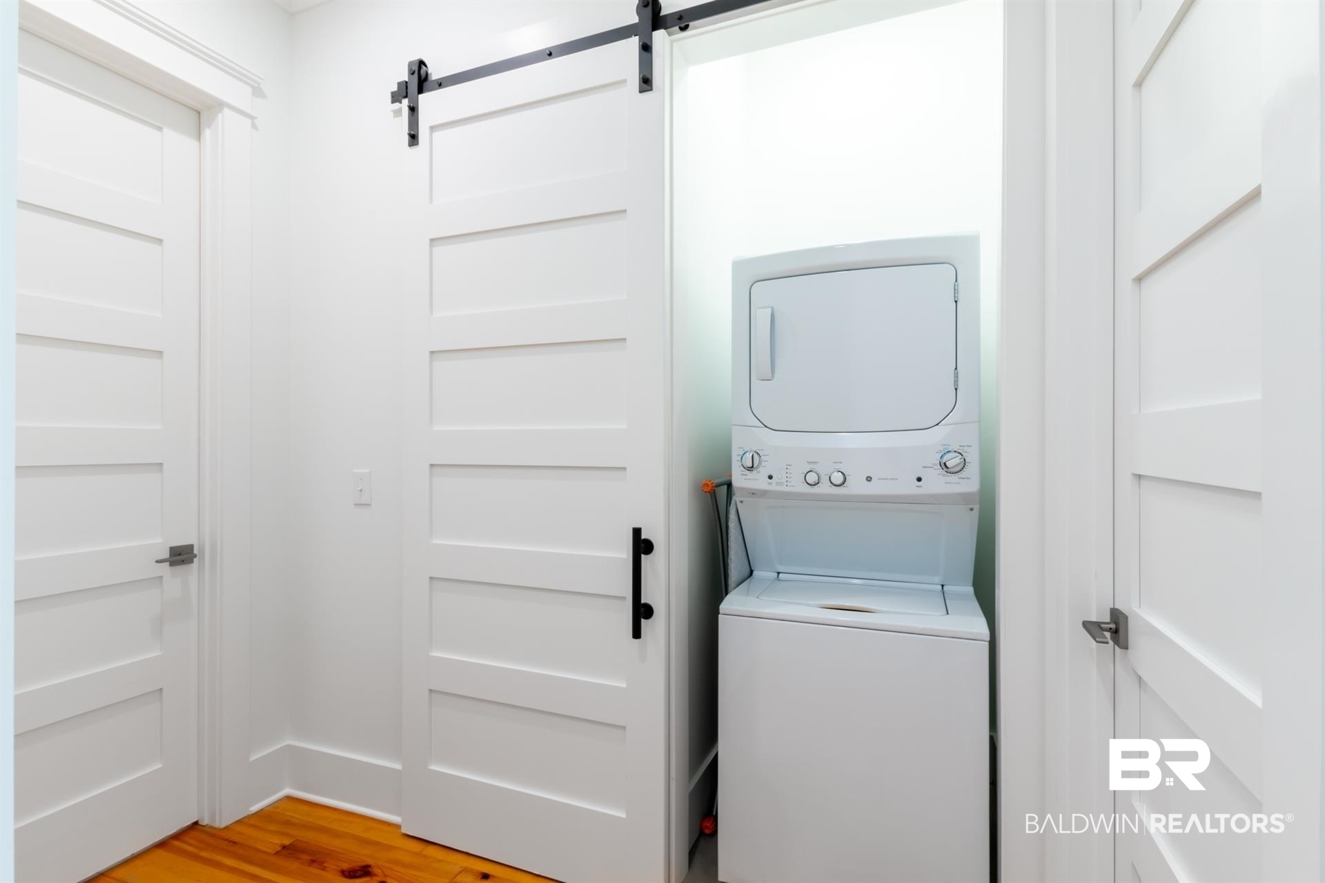 2494 Saltgrass Way Orange Beach, AL 36561 - Photo 19 of 37 Washroom with stacked washer and clothes dryer, a barn door, and wood-type flooring