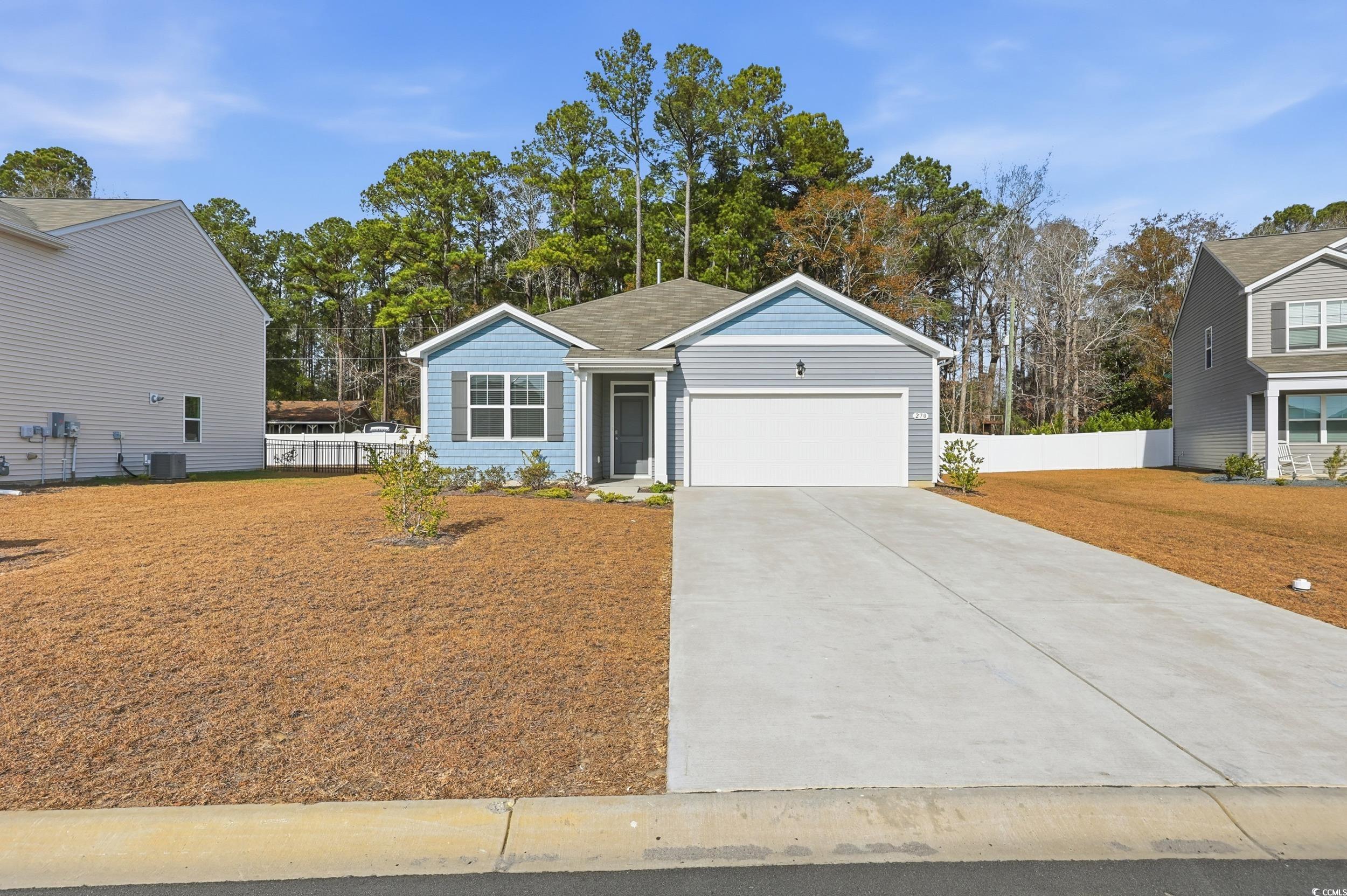 View of front facade featuring driveway, a garage, and view of scattered trees